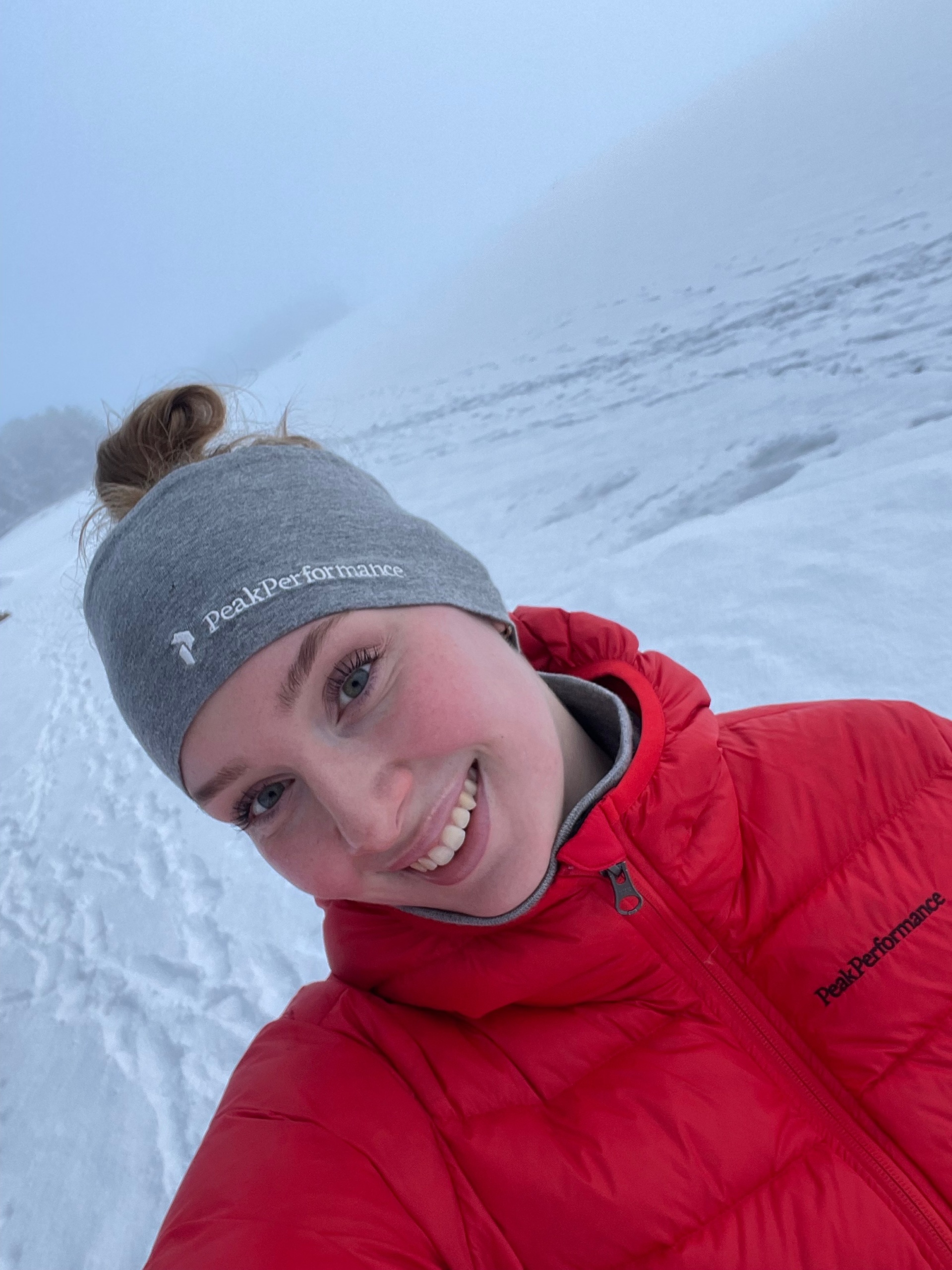 Nuori nainen hymyilee lumisen maiseman keskellä.