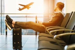 Mies istuu lentokentän penkillä ja katselee lentokoneen nousua.