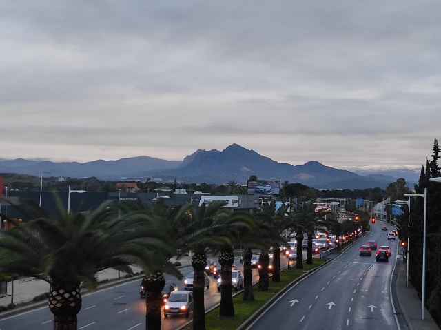 Kaupungin läpi menevä autotie, jonka keskellä on palmuja ja taustalla siintävät Espanjan vuoret.