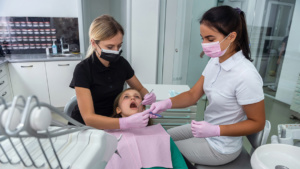 Hammaslääkäri ja hoitaja suorittamassa toimenpidettä hammaspotilaan kanssa.