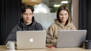 En ung pojke och en ung flicka arbetar med datorer.