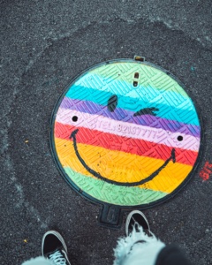 Lattiakaivon kanteen sateenkaaren väreillä maalattu hymynaama.