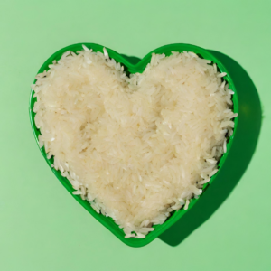 Riisiä sydänmenmuotoisessa astiassa vihreällä taustalla.