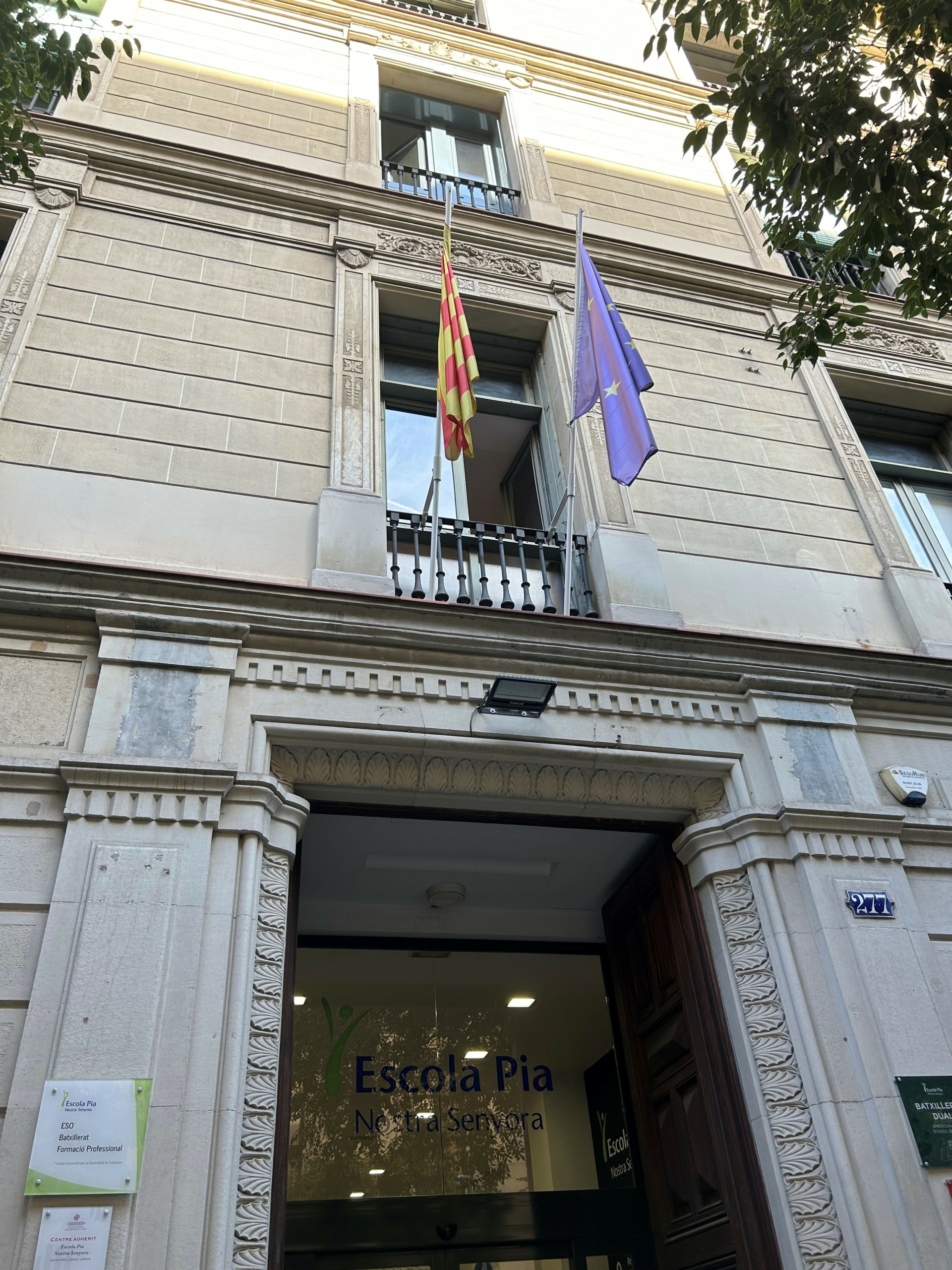 Kivitalon sisäänkäynti, jonka yläpuolella EU:n ja Katalonian lippu.