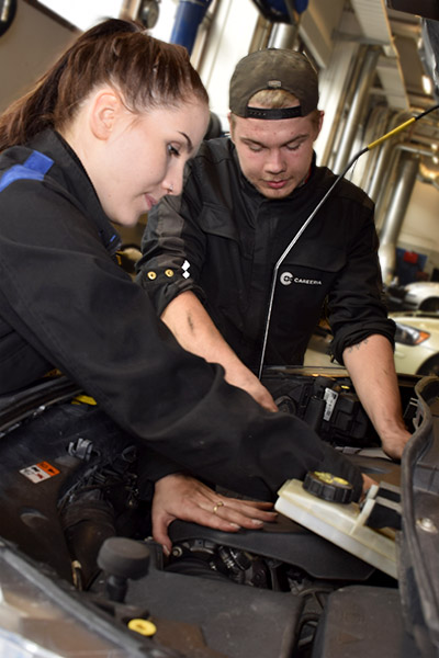 Kaksi ajoneuvoalan perustutkinnon opiskelijaa harjoittelee auton korjaamista.