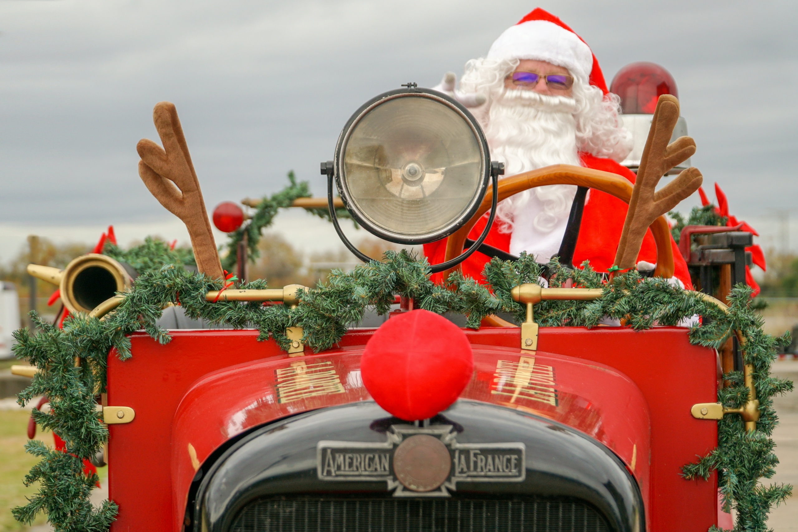 Joulupukki ajaa punaista autoa, jossa on edessä poron sarvet.