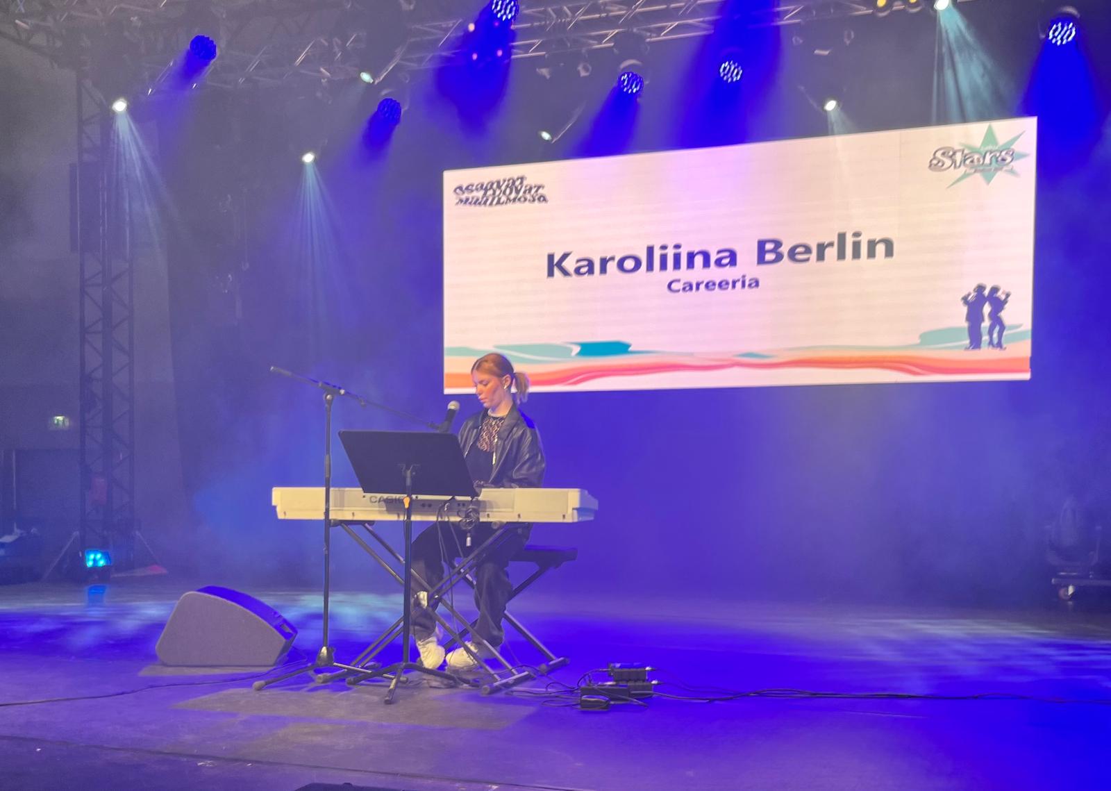 Nuori nainen lavalla soittamassa kosketinsoittimia. Taustalla heijastettuna teksti: Karoliina Berlin, Careeria.
