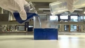 Läpikuultava malja, johon kaadetaan sinistä ja väritöntä nestettä.