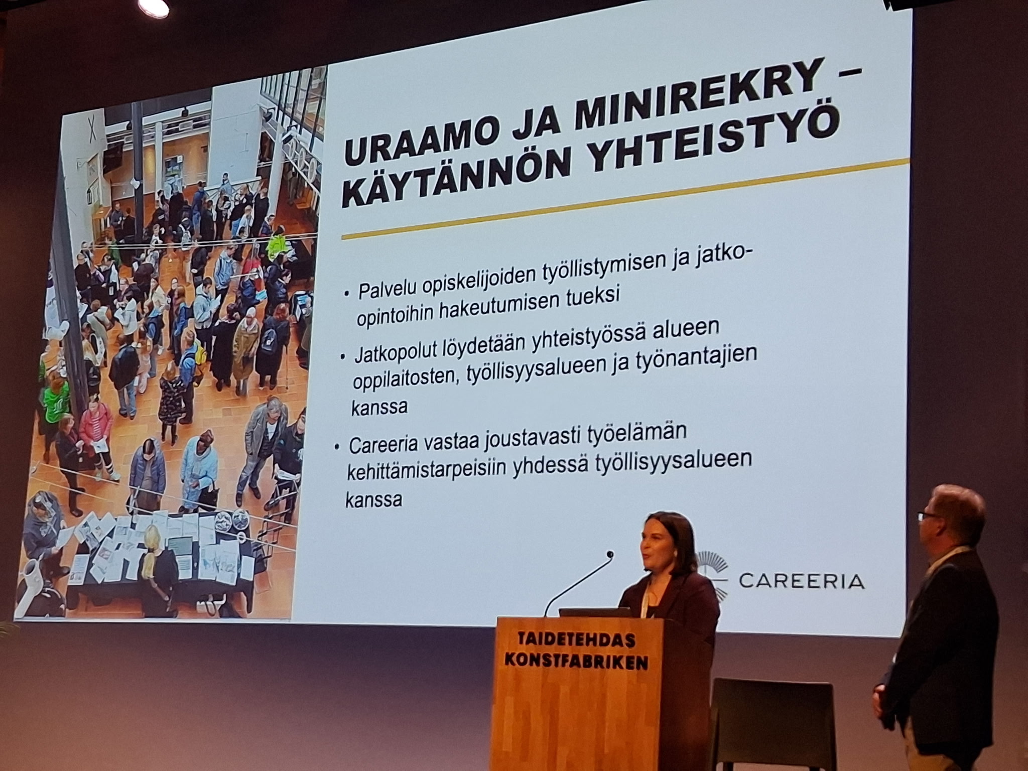 Nainen ja mies pitämässä esitystä. Taustalla dia, jossa kerrotaan Uraamosta ja Minirekrystä.