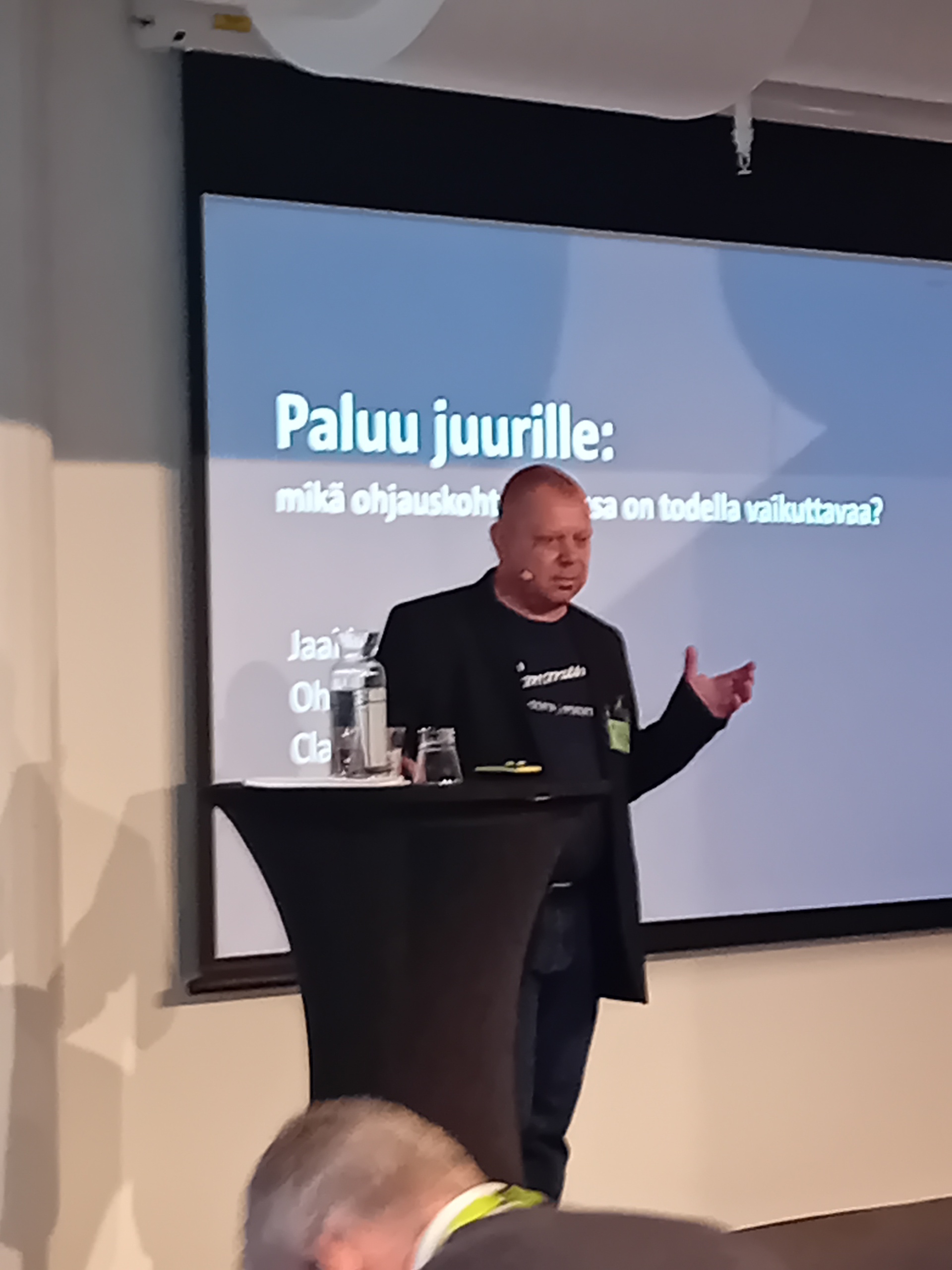 Mies pitämässä esitystä. Taustalla näkyy otsikko: Paluu juurille: mikä ohjauskohtaamisessa on todella vaikuttavaa?