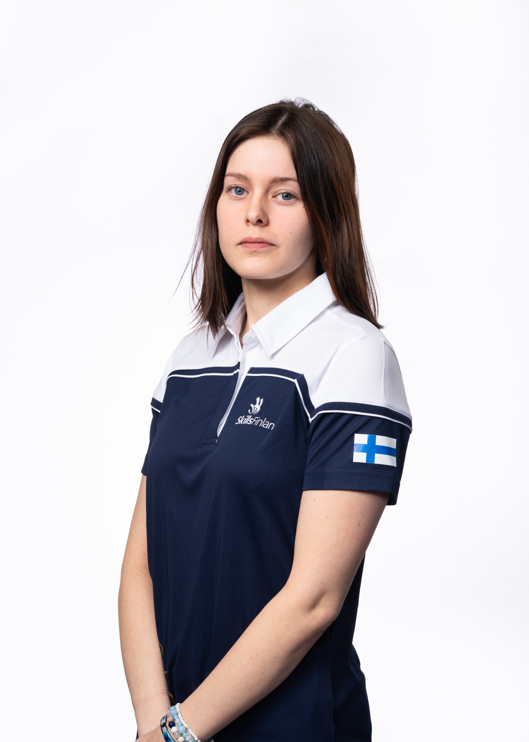 Nuori tummahiuksinen nainen yllään Skills Finlandin Suomen maajoukkueen edustuspaita.